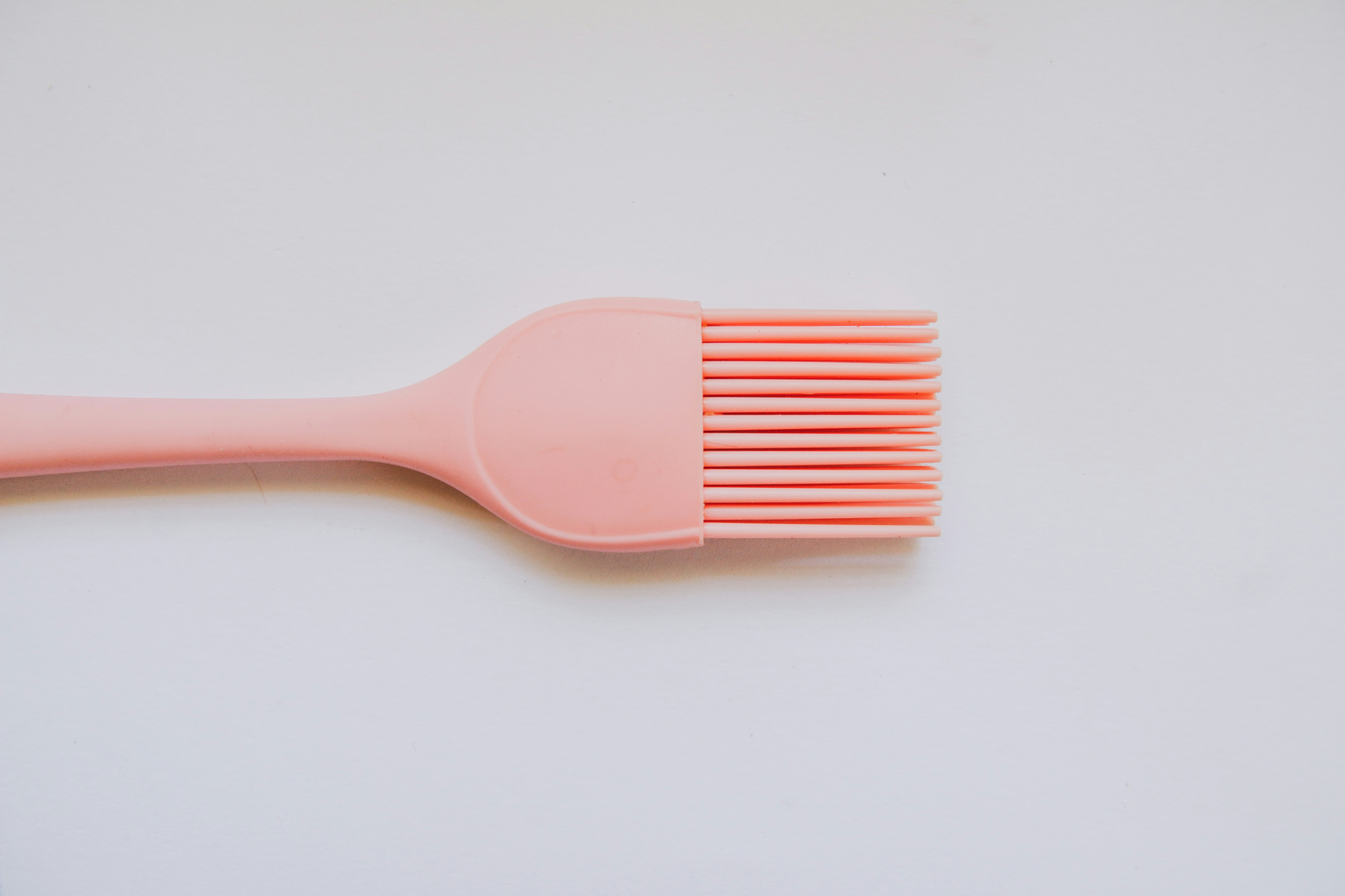 pink plastic hair comb on white surface